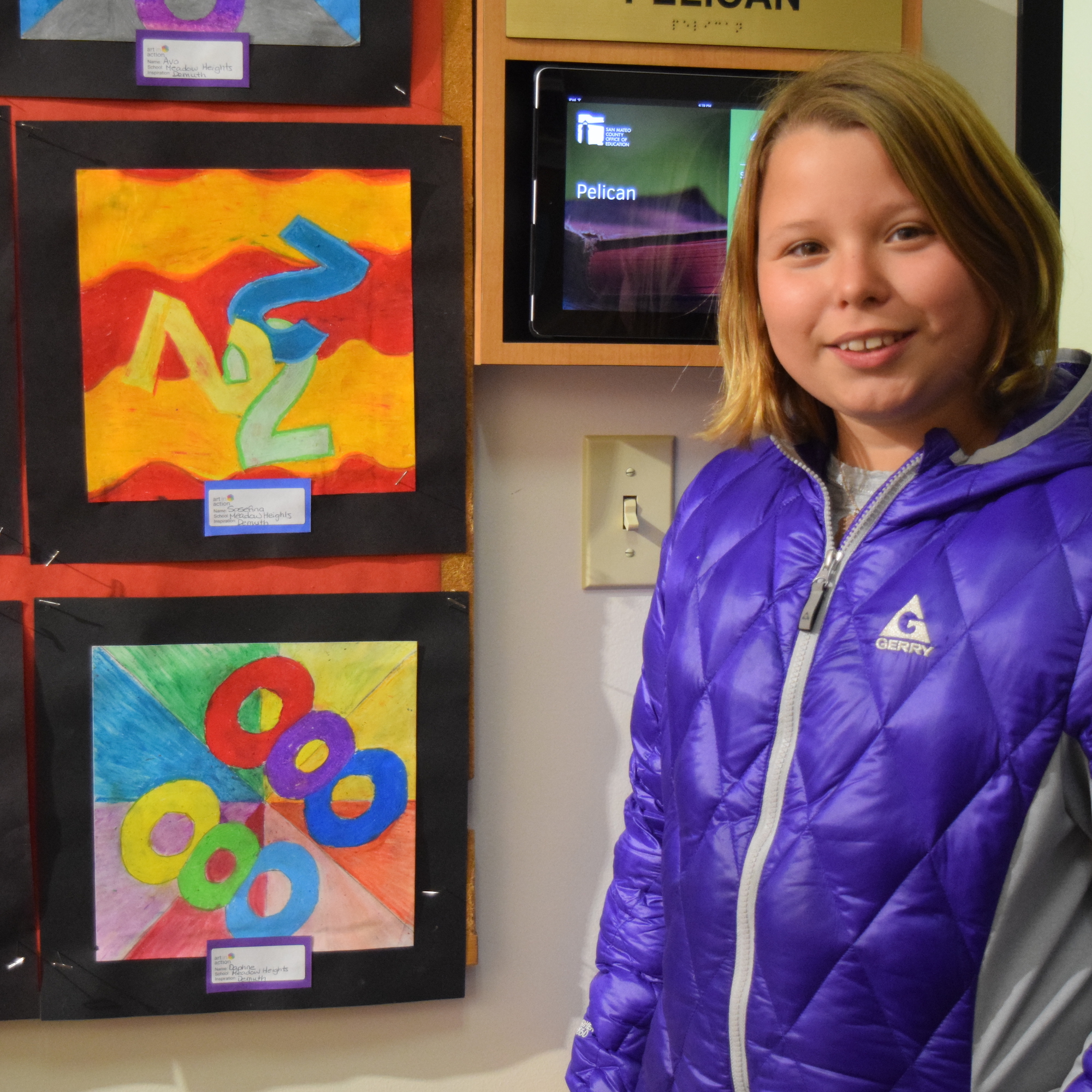 A student stands by her artwork displayed at the ɫTV.